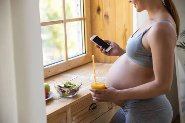 Smiling pretty pregnant lady holding mobile phone — ストック写真