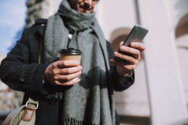 Yetişkin beyaz bir adam yeni cep telefonunu dışarıda kullanıyor.