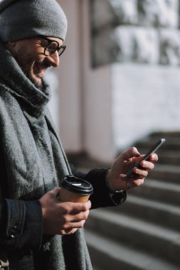 Yetişkin beyaz bir adam dışarıda cep telefonuyla sohbet ediyor.