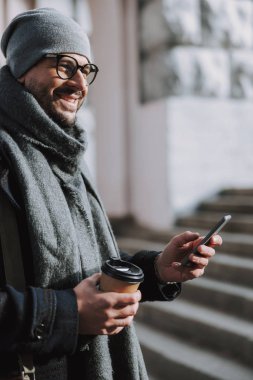 Yetişkin beyaz adam dışarıda birine gülümsüyor.
