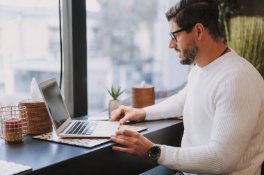 Laptop bilgisayarında çalışan beyaz, çekici bir adam.