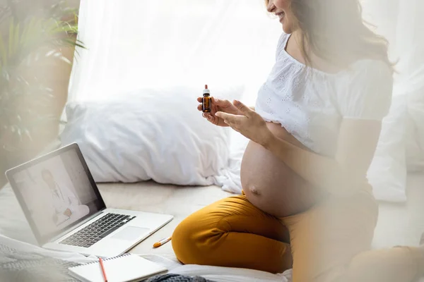 Lächelnde hübsche Schwangere mit Medikamenten im Bett — Stockfoto