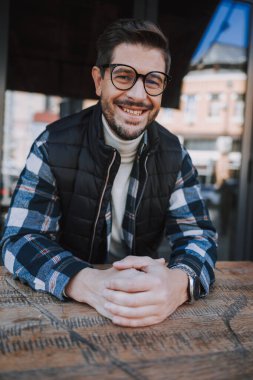 Gülümseyen yetişkin adam dışarıda dinleniyor.