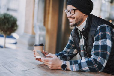 Kareli tişörtlü yakışıklı adam birine gülümsüyor.