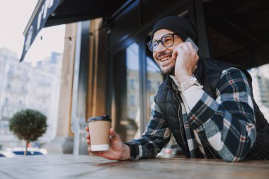 Dışarıdaki kameraya poz veren kareli gömlekli çekici bir adam.