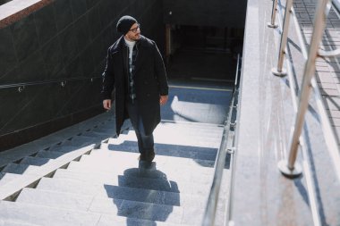 Beyaz adam çantasını saklıyor ve şehirde yürüyor.