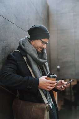 Beyaz elbiseli adam merdivenlerde kahve içiyor.