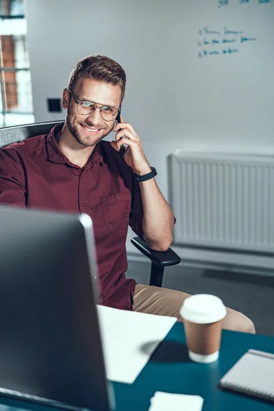 Sorrindo jovem está usando telefone celular — Fotografia de Stock