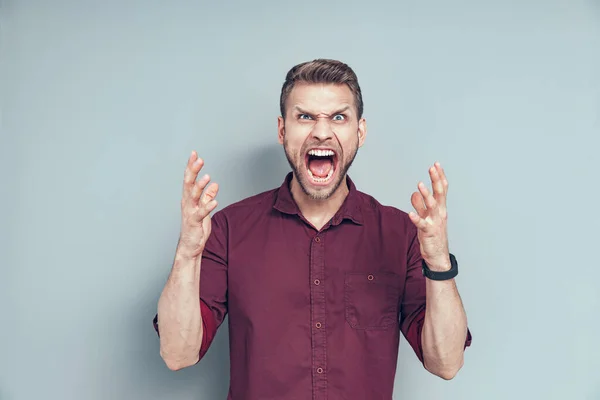 Young man is holding hands up in studio — Stock Photo, Image