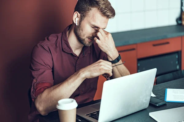 Tired male employee holding hand on nose bridge