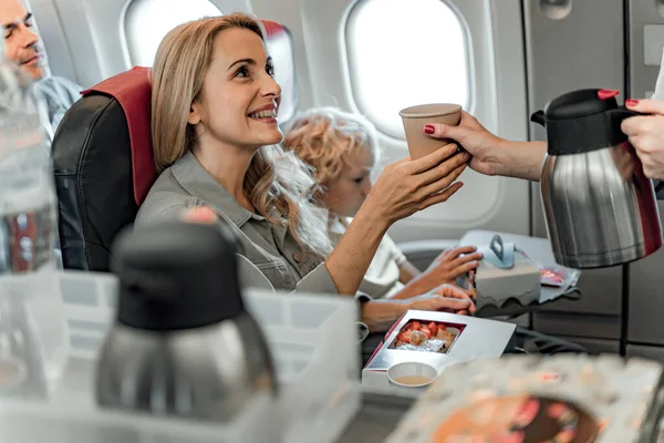 Красивая улыбающаяся женщина держит горячий напиток в самолете — стоковое фото