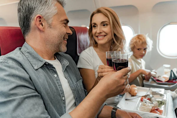 Улыбающиеся мужчина и женщина держат бокалы с вином в самолете — стоковое фото