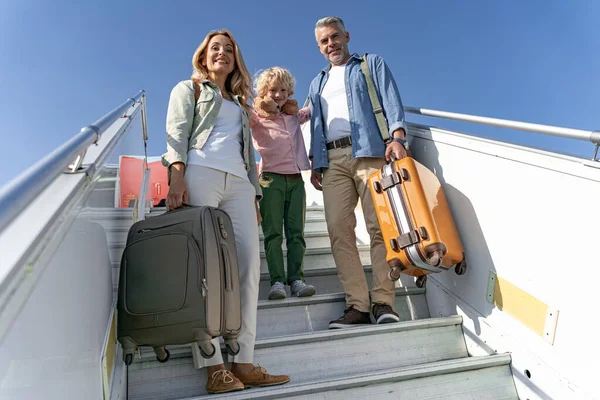 Familia sonriente con maletas grandes cerca del avión — Foto de Stock