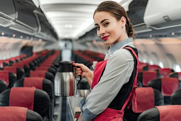 Bella giovane hostess aerea è in piedi in cabina — Foto Stock