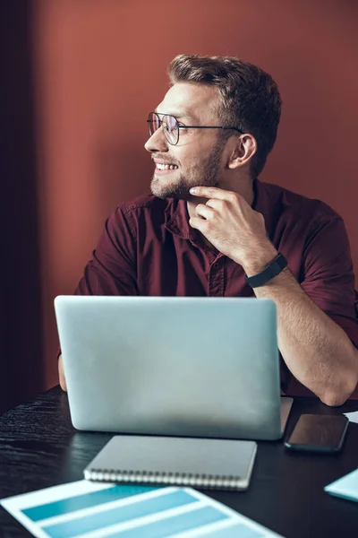 Smiling young man looking away at the table — Stock Photo, Image