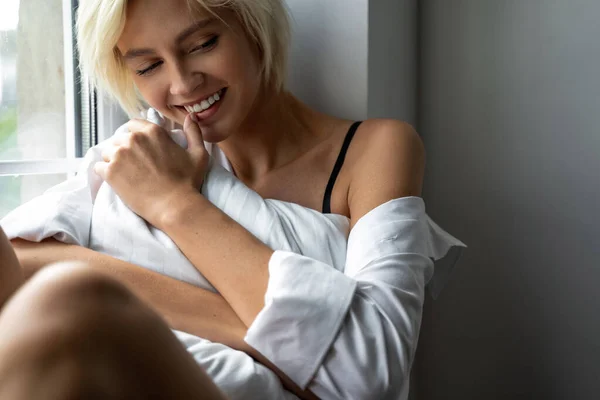 Happy young lady dreaming on the windowsill — Stock Photo, Image