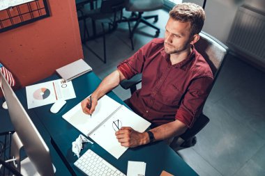 Genç bir erkek çalışan monitör ekranına bakıyor.