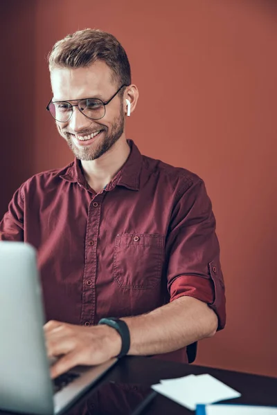 Un jeune homme souriant porte des écouteurs au bureau — Photo