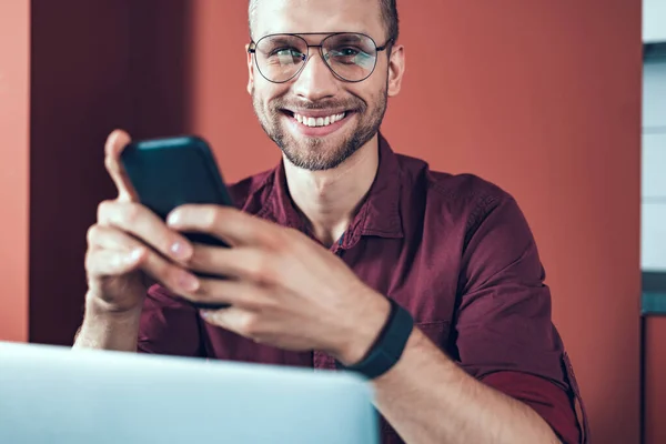 Glad ung man sitter med mobiltelefon — Stockfoto