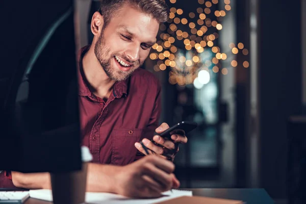 Joyeux jeune homme travaillant le soir à son bureau — Photo