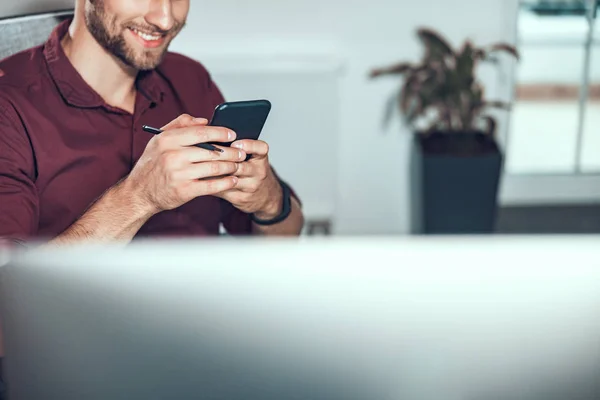 Un jeune homme souriant écrit un message au téléphone — Photo