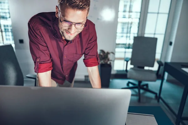 Un jeune homme souriant qui travaille avec un ordinateur dans son bureau — Photo