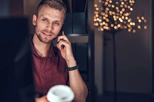 Sonriente trabajador masculino está utilizando el teléfono móvil en la oficina — Foto de Stock