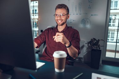 Masada oturan gülümseyen genç adam.