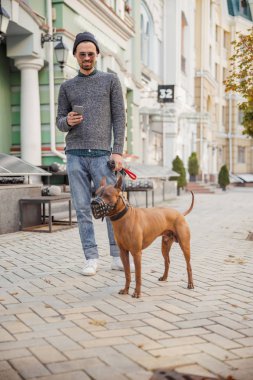 Sokaktaki memnun adam, elinde köpek resmi olan.