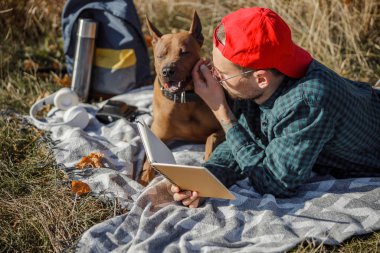 Defterli rahat bir adam köpek stoğundaki fotoğrafı okşuyor.
