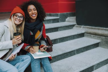 Genç beyaz ve Afro Amerikalı kadınlar sırıtıyor.