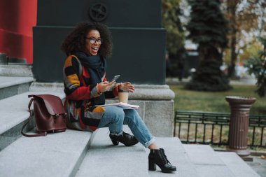 Mutlu Afro-Amerikan kadın gülüyor ve merdivenlerde oturuyor