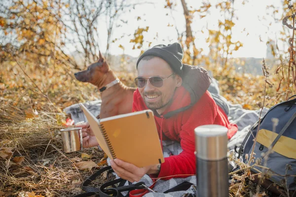 Happy man with tea and notebook in forest stock photo — Stock Photo, Image