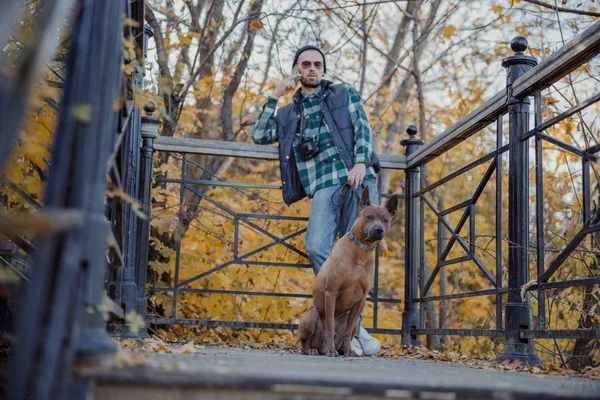 Ein ernsthafter Mann mit Hund steht am Geländer Archivbild — Stockfoto