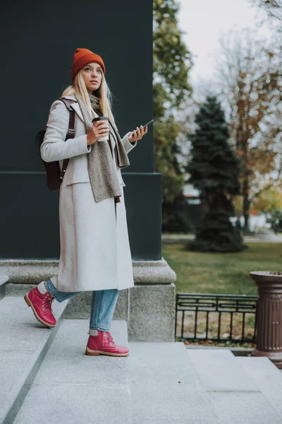 Красивая девушка с кофе и смартфоном ходит по улице — стоковое фото