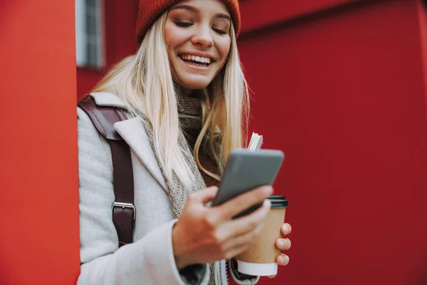 Giovane donna con caffè utilizzando smartphone e sorridente ampia — Foto Stock