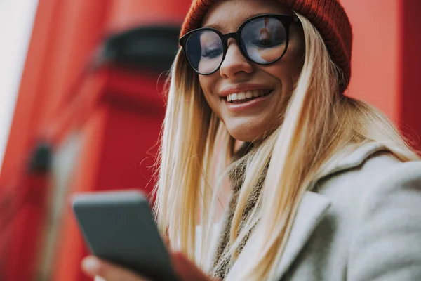 Jovem mulher com smartphone moderno sorrindo largo — Fotografia de Stock