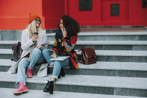 Young Caucasian and Afro American females talking on smartphone — 스톡 사진