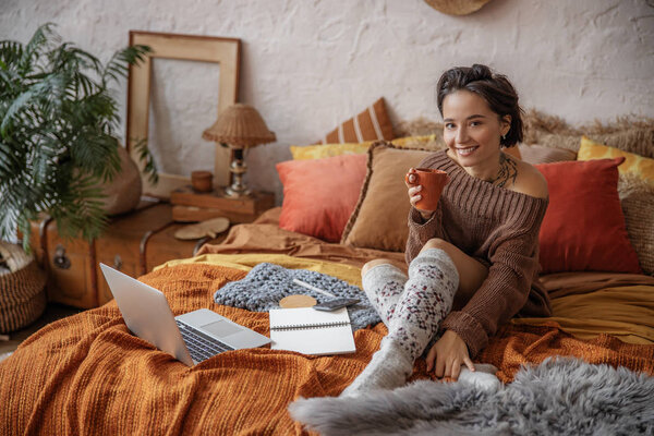 Улыбающаяся красавица позирует перед камерой с чашкой.
