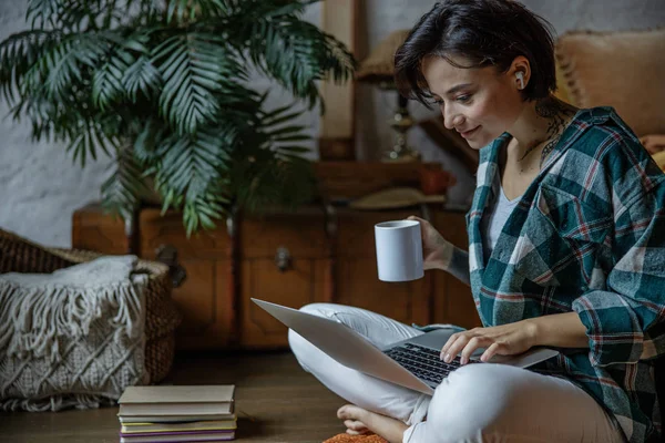 Mujer sonriente está trabajando con el ordenador portátil en la habitación —  Fotos de Stock