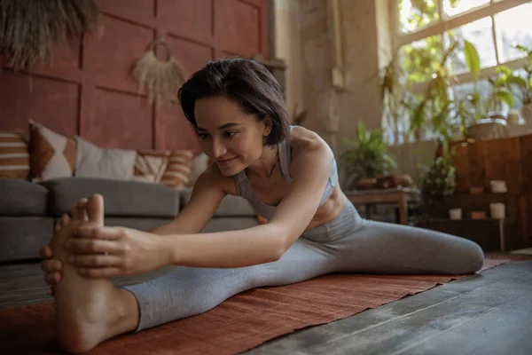 Sorrindo jovem mulher está fazendo exercício pilates — Fotografia de Stock