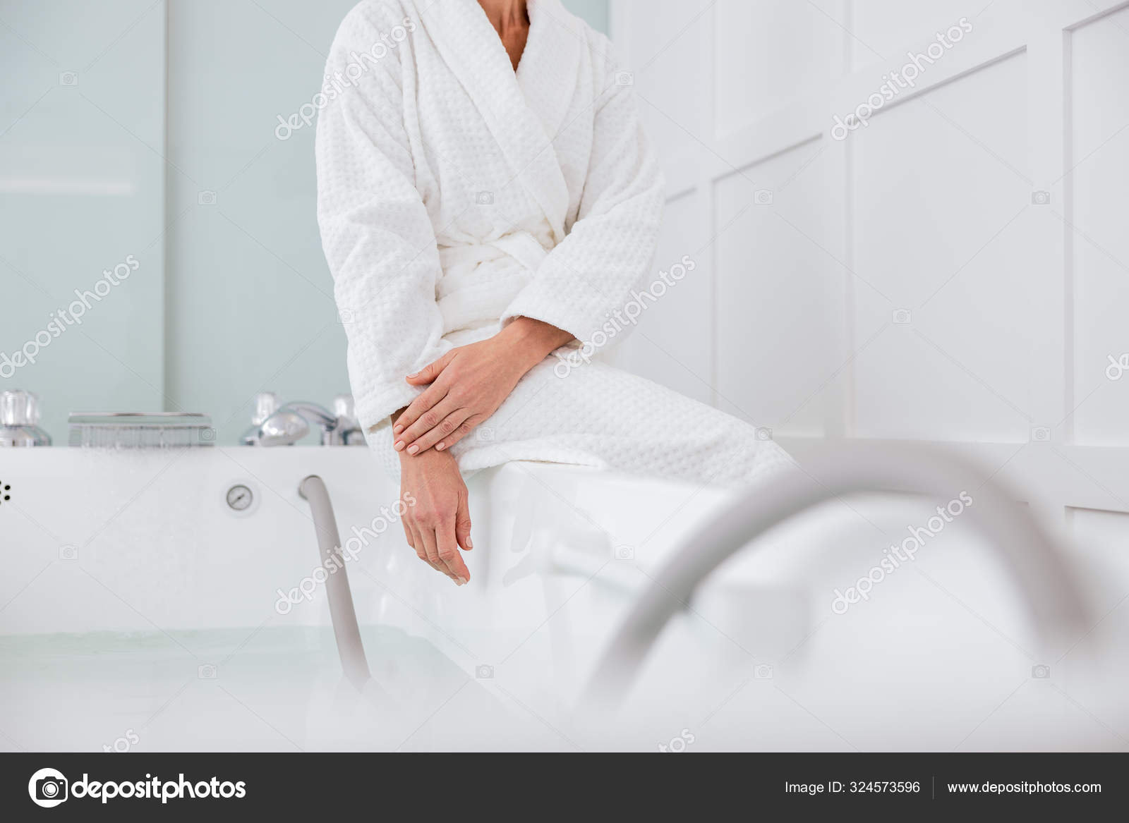 Woman wearing white bathrobe and sitting near the hot tub Stock Photo