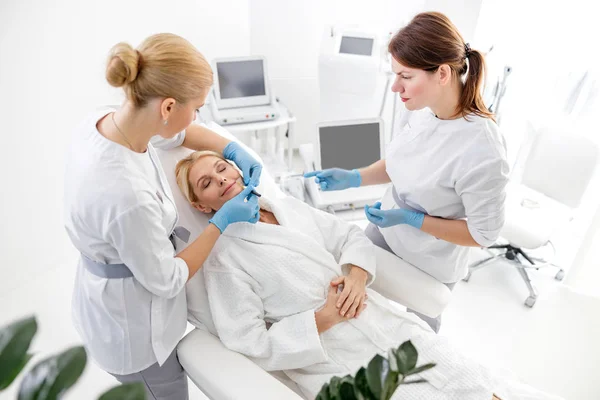 Doctor dibujando una rejilla en la cara antes del procedimiento de elevación — Foto de Stock