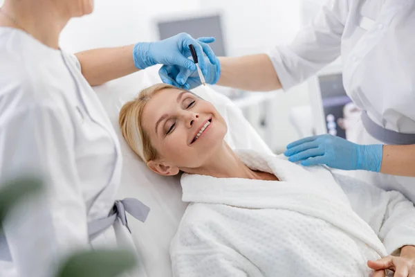 Mujer adulta sonriente con los ojos cerrados en el sofá en el salón de belleza — Foto de Stock