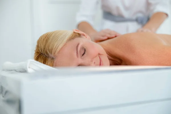 Усміхнена жінка має класичний масаж шиї та спини — стокове фото