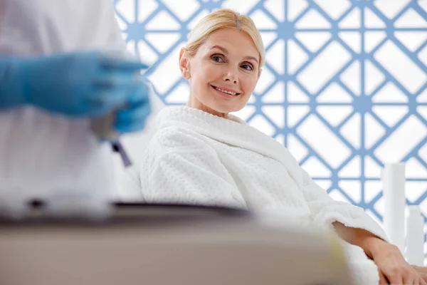 Happy woman looking at how the beautician working — Stockfoto