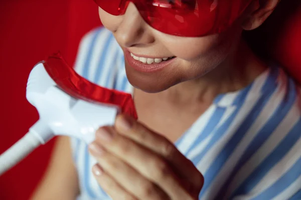 Smiling lady receiving teeth whitening procedure in beauty center — Stockfoto