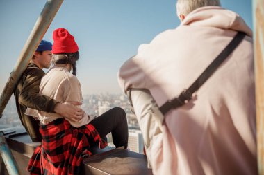 Genç adam çatıda kız arkadaşına sarılıyor.