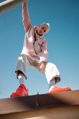 Havalı bir adam çatıda kameraya bakıyor.