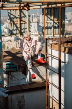 Gülümseyen stil sahibi adam çatıya bakıyor.